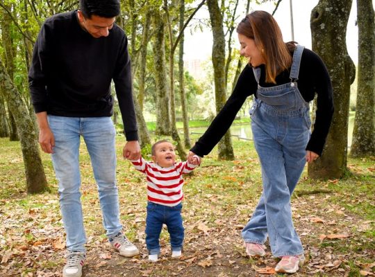 A joyful family enjoys a walk under lush green trees in the park.