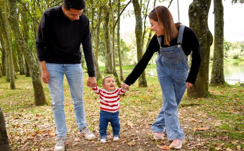 A joyful family enjoys a walk under lush green trees in the park.